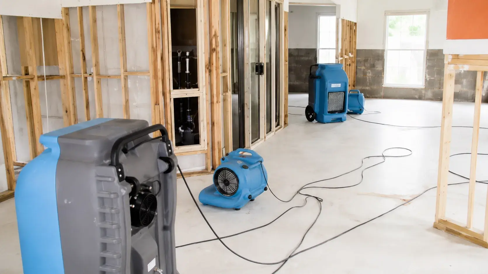 Industrial air movers and dehumidifiers drying out a gutted structure down to the studs